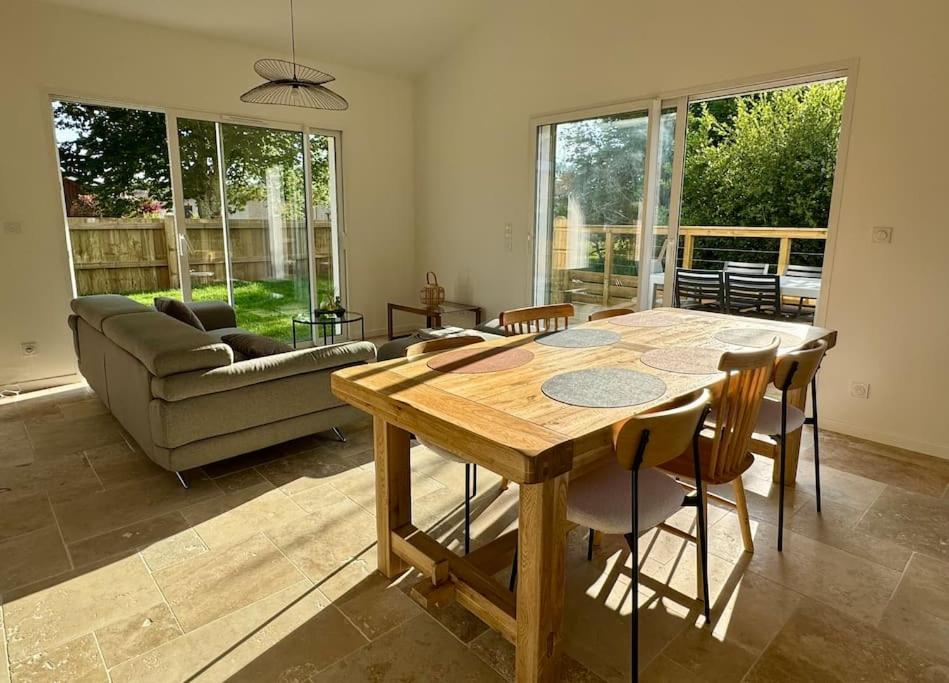 un salon avec une table et des chaises en bois dans l'établissement Villa à deux pas du Lac, à Léon