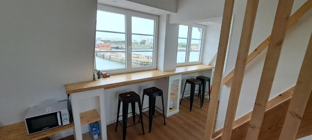 une pièce avec un comptoir avec des tabourets sous une fenêtre dans l'établissement L'escale marine, à Calais