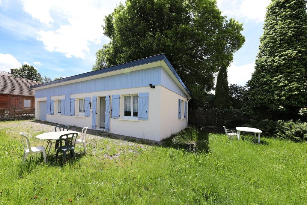 une petite maison blanche avec une table et des chaises dans un champ dans l'établissement Maison les Lilas, à Gérardmer