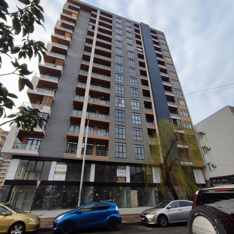 a tall building with cars parked in front of it at Home Side Apartment in Batumi