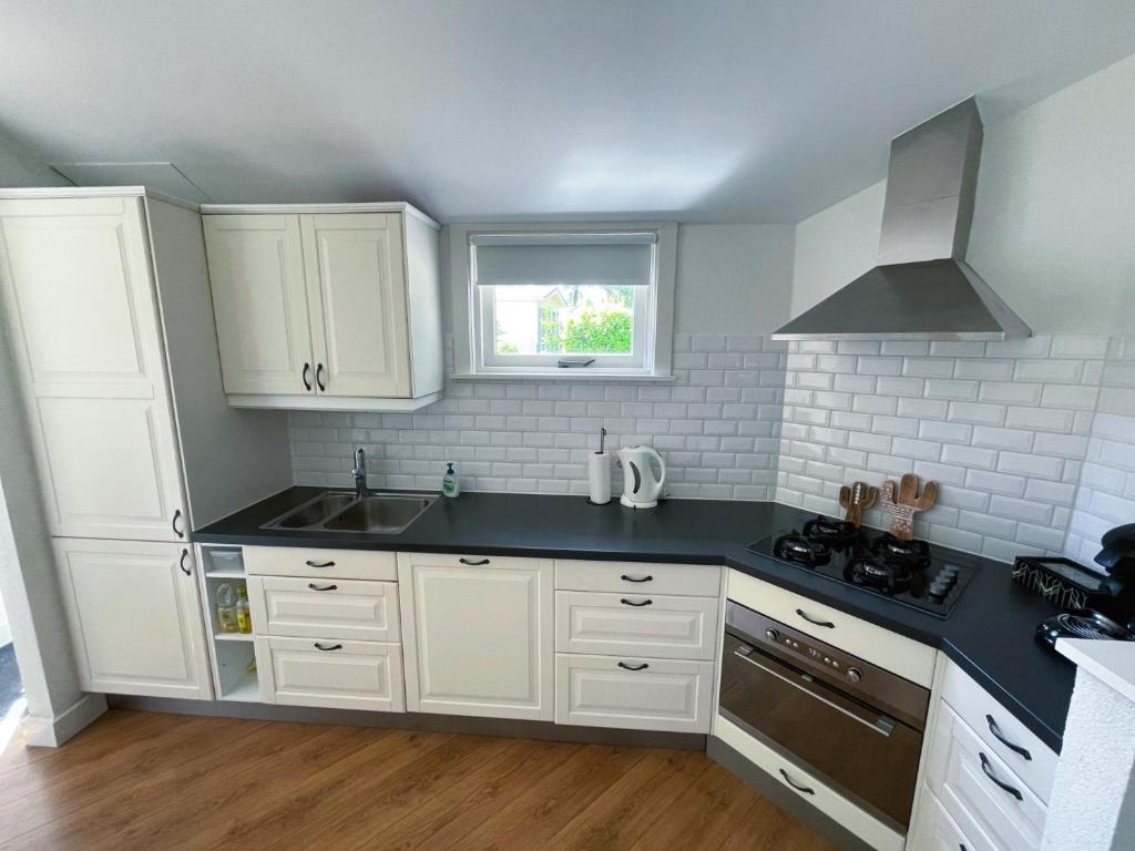 een keuken met witte kasten en een zwart aanrecht bij FELICITY - Family Home in the forest in Beekbergen