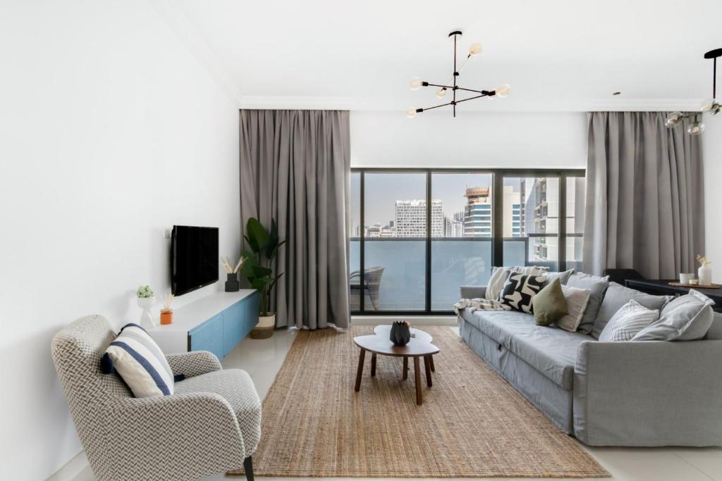 ein Wohnzimmer mit Sofa, Sesseln und Fernseher in der Unterkunft GuestReady Holiday Homes - Light Abode in Dubai