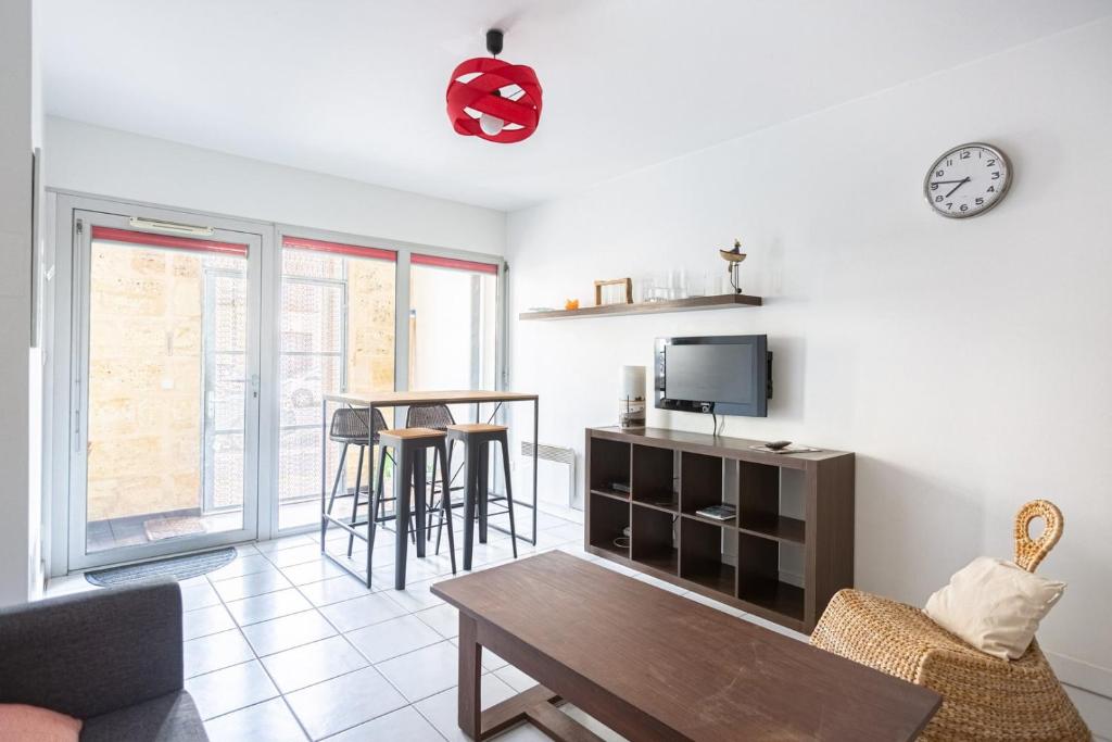 a living room with a table and a tv at GuestReady - Appartement Cours du Médoc in Bordeaux