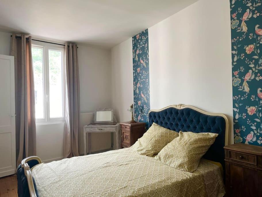 una camera da letto con un letto con testiera blu e una finestra di Charmante maison Girondine a La Rivière