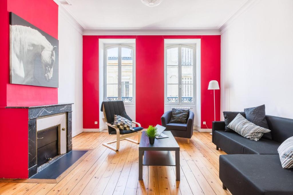 Elle comprend un salon doté de murs rouges et d'une cheminée. dans l'établissement GuestReady - Duplex lumineux et spacieux, 7 personnes, à Bordeaux