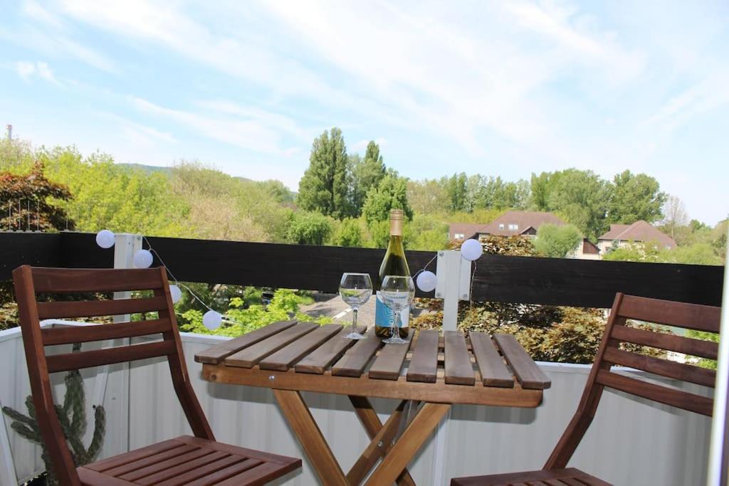 a wooden table with two glasses of wine on a balcony at Apartment close to Sziget festival in Budapest