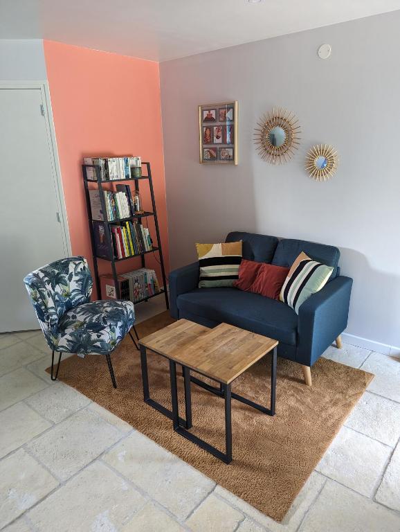 un salon avec un canapé bleu et une chaise dans l'établissement Joli studio à la campagne, à Lassay