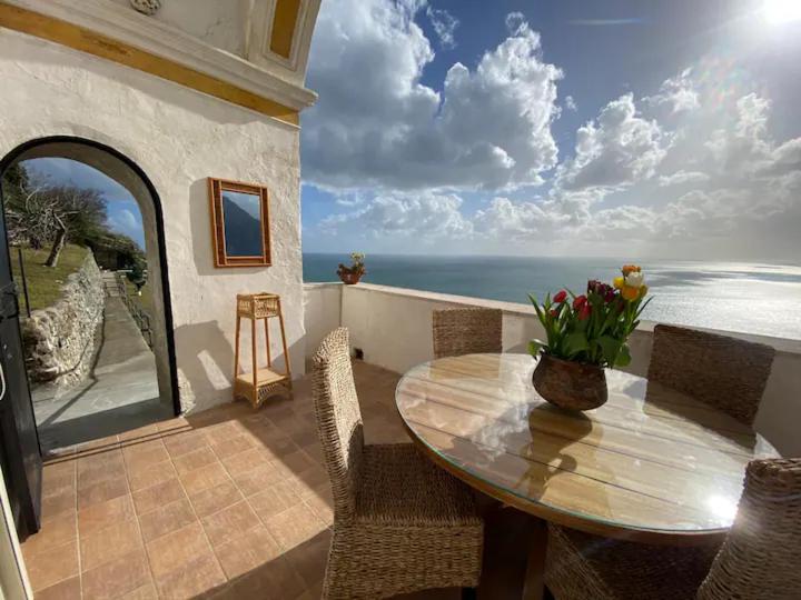 a table on a balcony with a view of the ocean at Limoni in Praiano