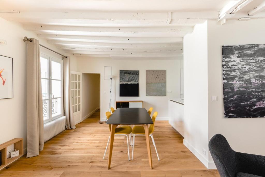 jadalnia z czarnym stołem i żółtymi krzesłami w obiekcie GuestReady - Estadia tranquila em Le Marais w Paryżu
