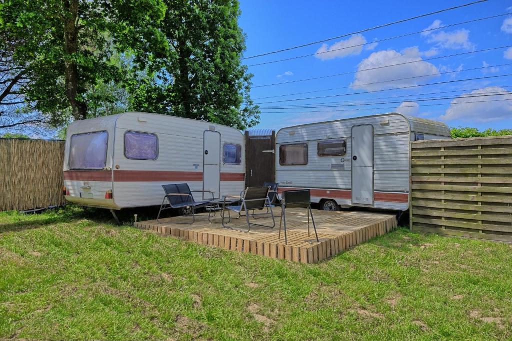 deux camping-cars garés dans une cour avec des chaises et un patio dans l'établissement L'échappée Belle, à Saint-Maudez