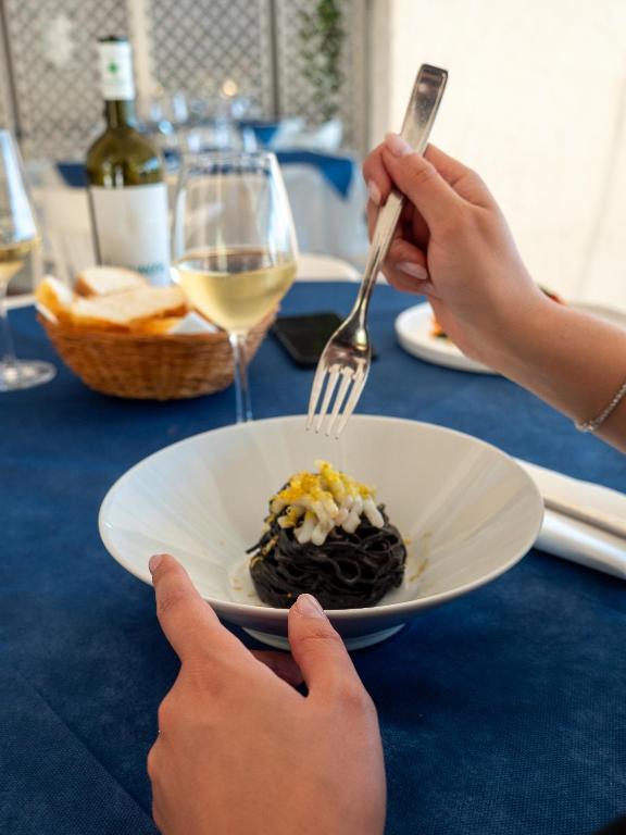 a person holding a fork and a plate of food at Hotel Il Perseo in Chiessi