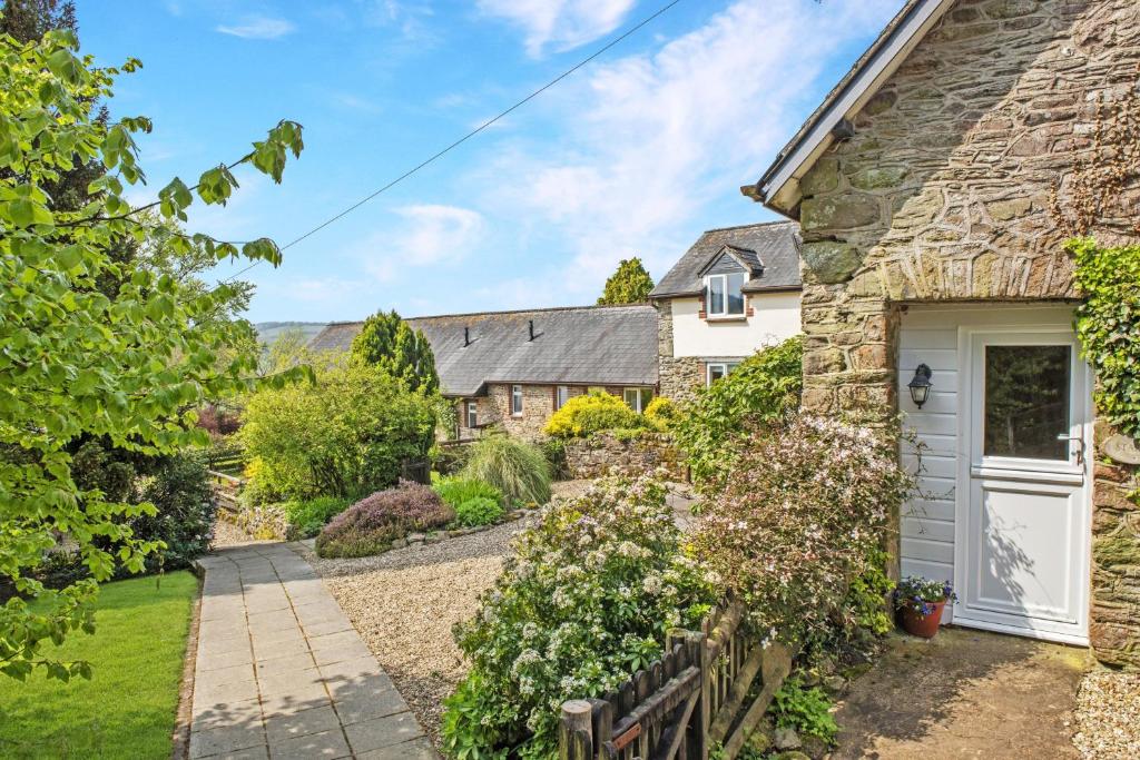 un cottage in pietra con una porta bianca e un giardino di Stable Cottage Wheddon Cross a Minehead
