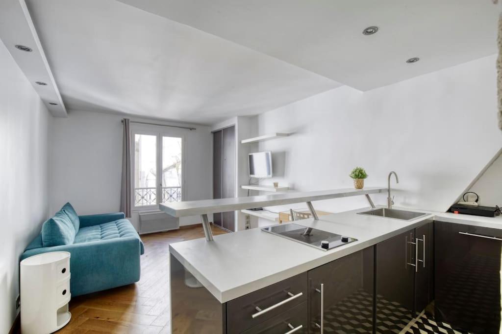 une cuisine avec un évier et un canapé bleu dans l'établissement Studio Charmant à Deux Pas de l'Élysée Luxe et Confort au Cœur de Paris, à Paris