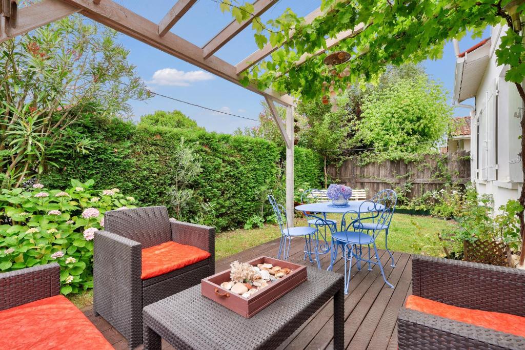 un jardin avec une table, des chaises et une pergola dans l'établissement À 400m de la plage, maison pour 8 avec piscine, à Andernos-les-Bains