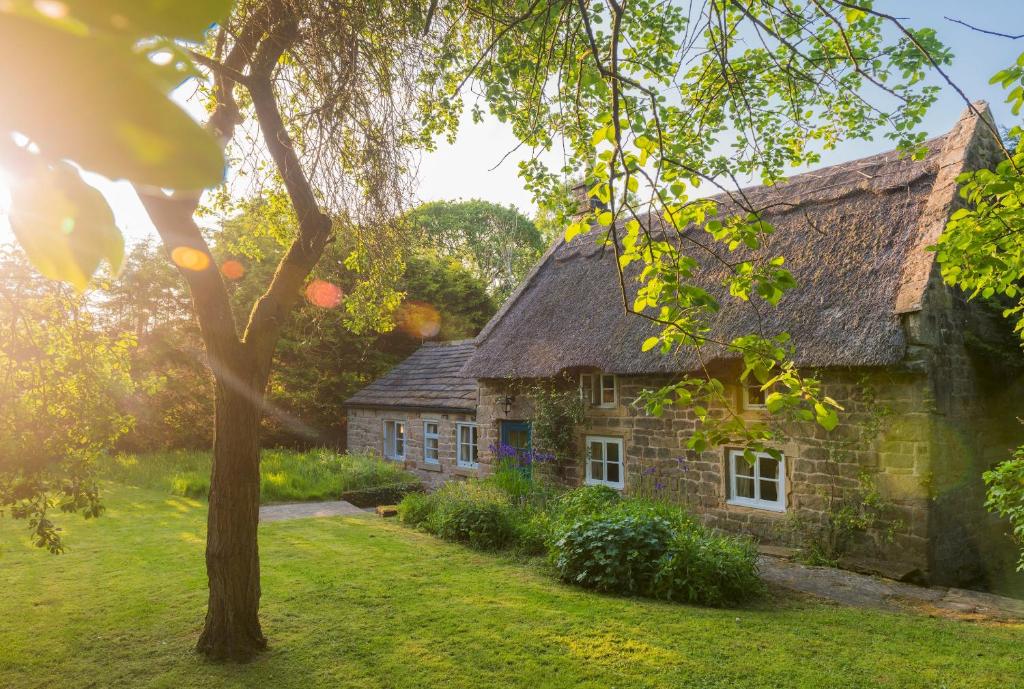 an old stone house with a thatched roof at Park CottageChatsworth Estate in Baslow
