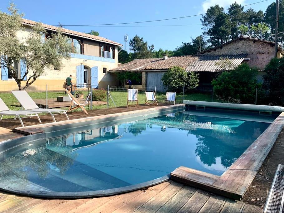a swimming pool with chairs and a house at Evasion enchantée, maison au cœur de la forêt in Léogeats