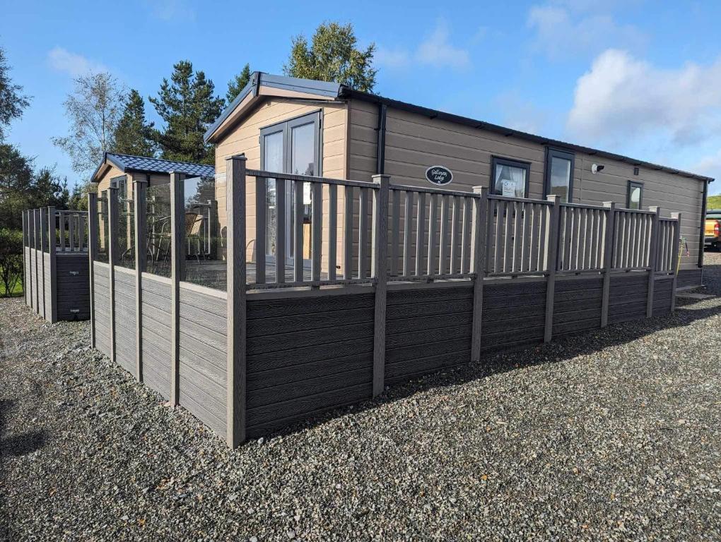 a small house with a wooden fence at Newton Stewart - Lodge - Sleeps 4 - Garden in Bargrennan