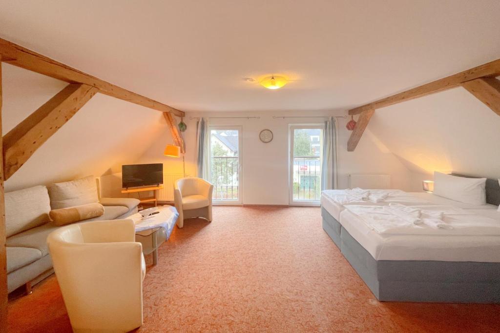 a bedroom with a bed and a couch and a tv at Haus Antje Studio in Kölpinsee