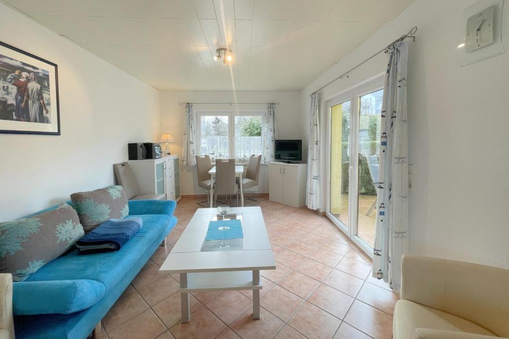 een woonkamer met een blauwe bank en een tafel bij Haus Antje Gartenbungalow in Kolpinsee
