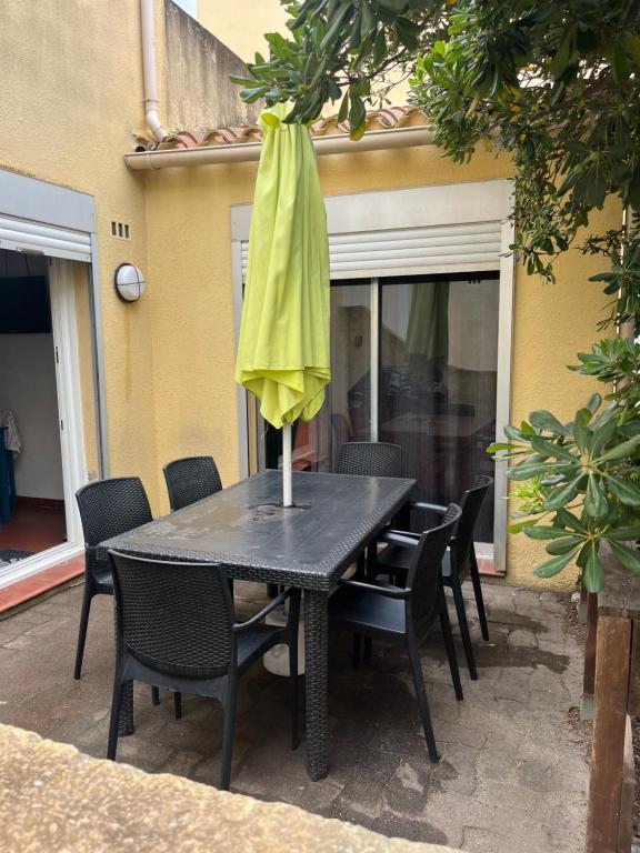 une table avec un parapluie jaune au-dessus dans l'établissement Maison, au Barcarès