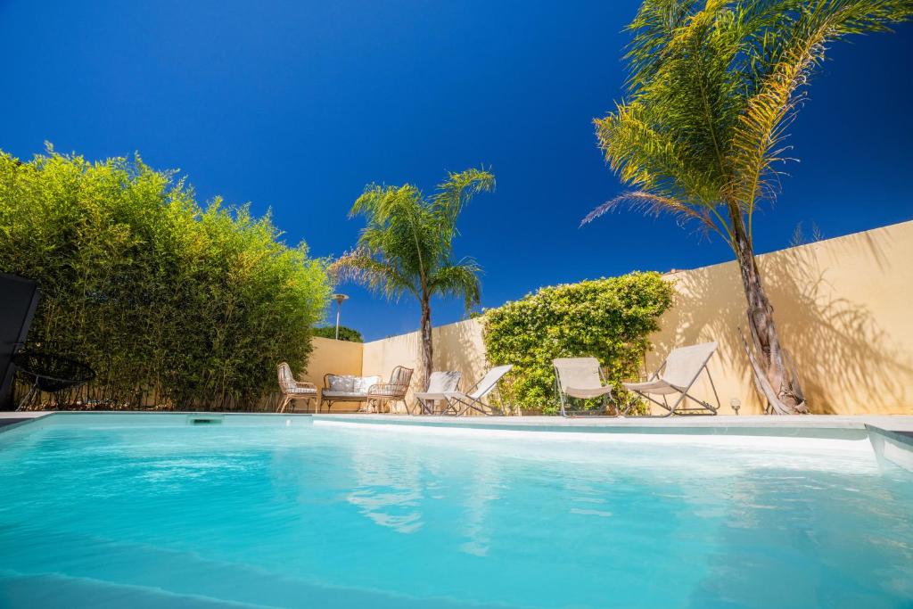 basen z krzesłami i palmami w obiekcie VILLA COSYFAMILY PISCINE WIFI 15MIN PLAGE idéal FAMILLE - TopProsConciergerie w mieście Pérols