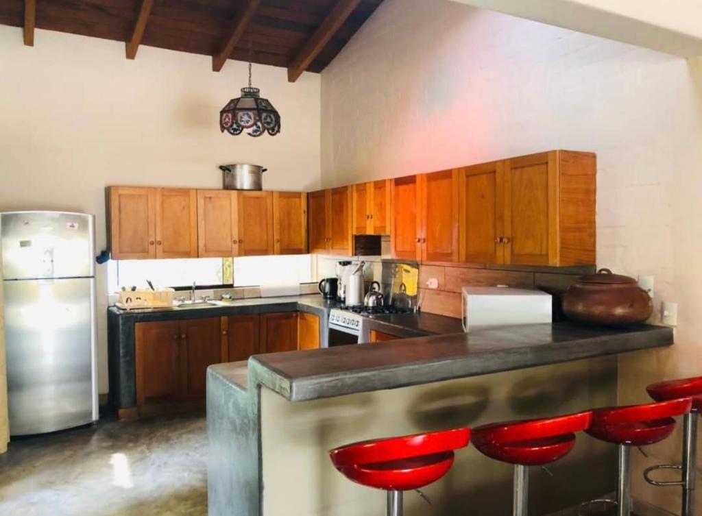 a kitchen with wooden cabinets and red bar stools at Casa de campo El Valle Inn in Lima