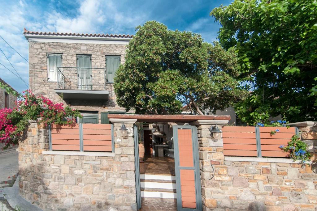 a stone house with a gate and a stone wall at Nephelis Heritage House in Moúdhros
