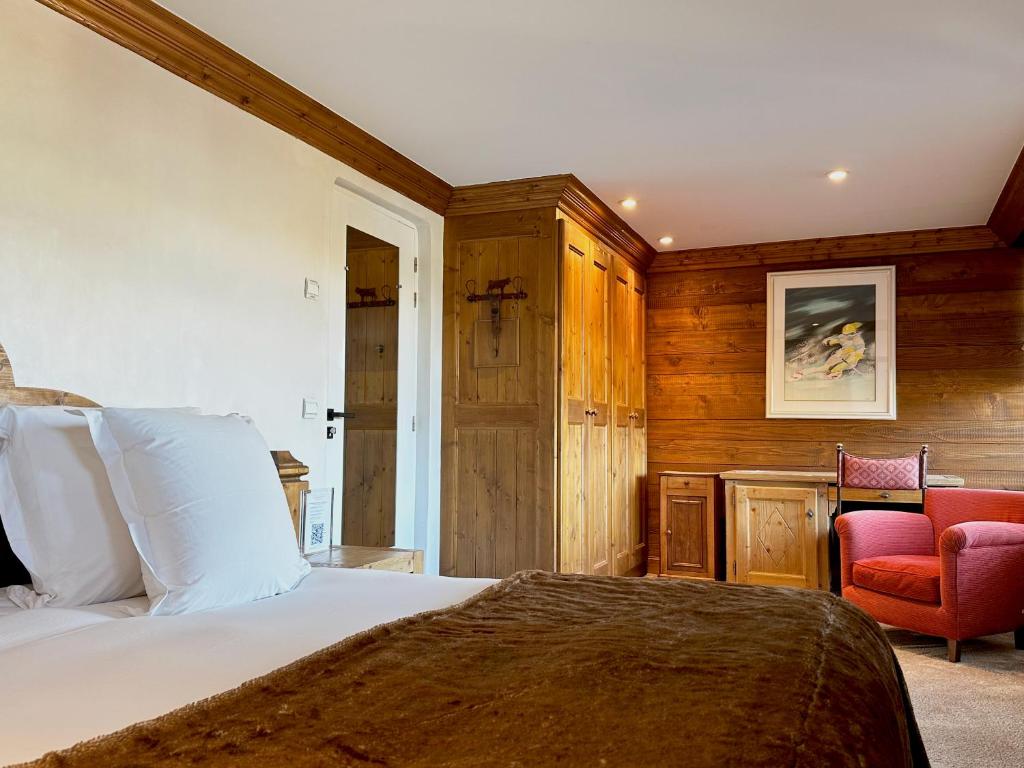 a bedroom with a bed and a red chair at Hôtel Les Peupliers in Courchevel