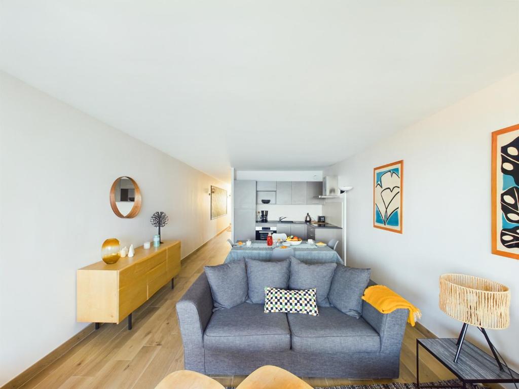 Una sala de estar con un sofá azul y una cocina. en -PAOLO- Beau T2 avec Vue Mer et Parking, en Concarneau