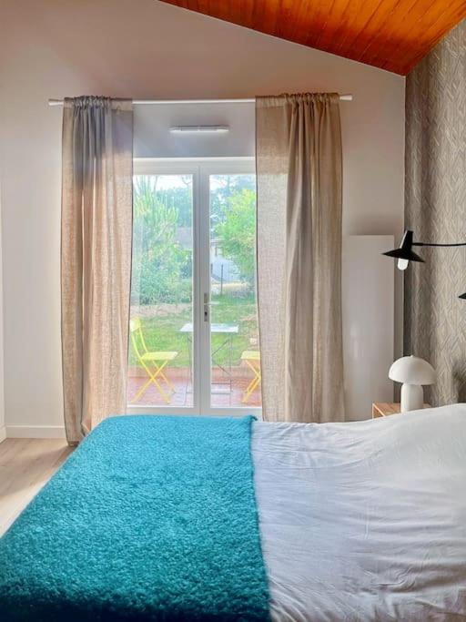 une chambre avec un lit et une porte coulissante en verre dans l'établissement T2 cosy proche golf et plage, à Capbreton