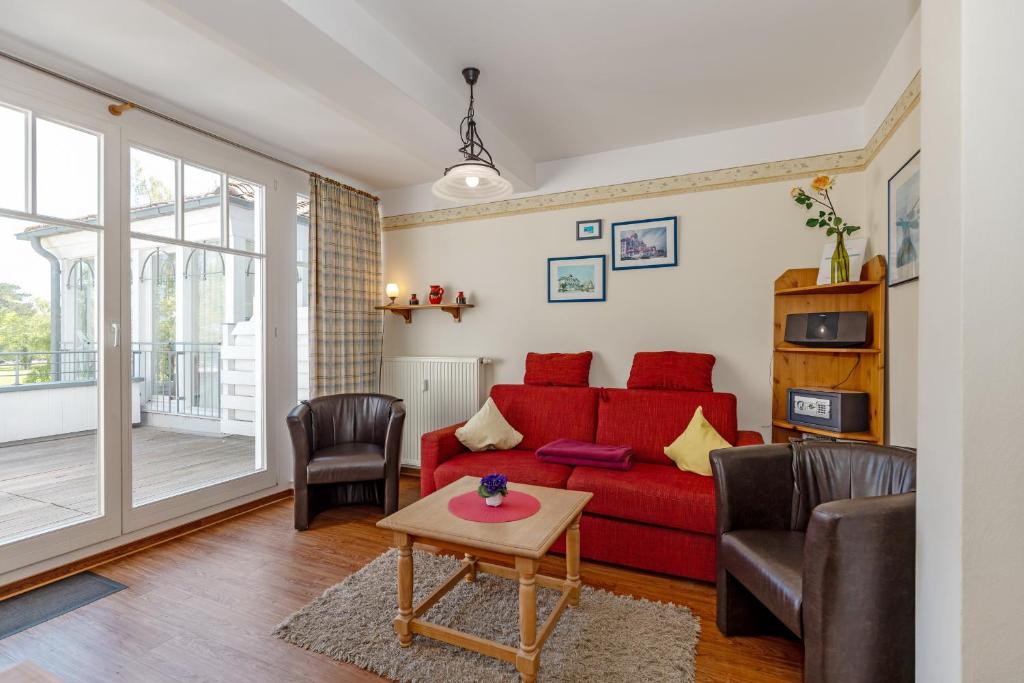 ein Wohnzimmer mit einem roten Sofa und Stühlen in der Unterkunft Meeresblick Meeresblick 206 in Kühlungsborn