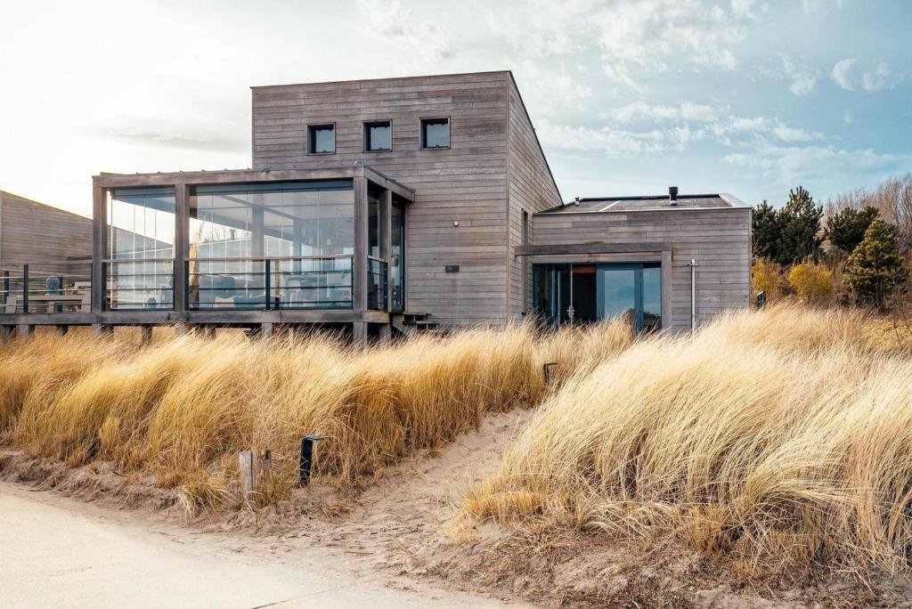 a house on the side of a hill with tall grass at Panorama Beach Villa 4p - Premium Comfort & Uitzicht - Villa 25 in Ouddorp