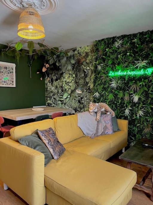 - un salon avec un canapé jaune et un mur vert dans l'établissement La cabane tropicale, à Pontorson