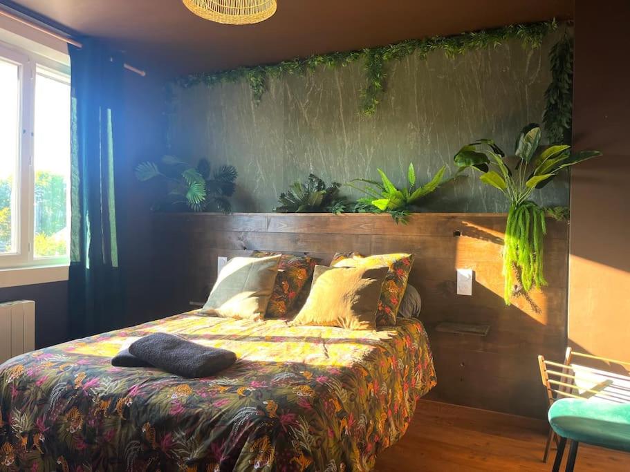 a bedroom with a bed with plants on the wall at La cabane tropicale in Pontorson