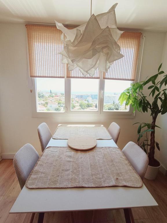 une table de salle à manger avec des chaises et une grande fenêtre dans l'établissement Nid cosy, à Nice