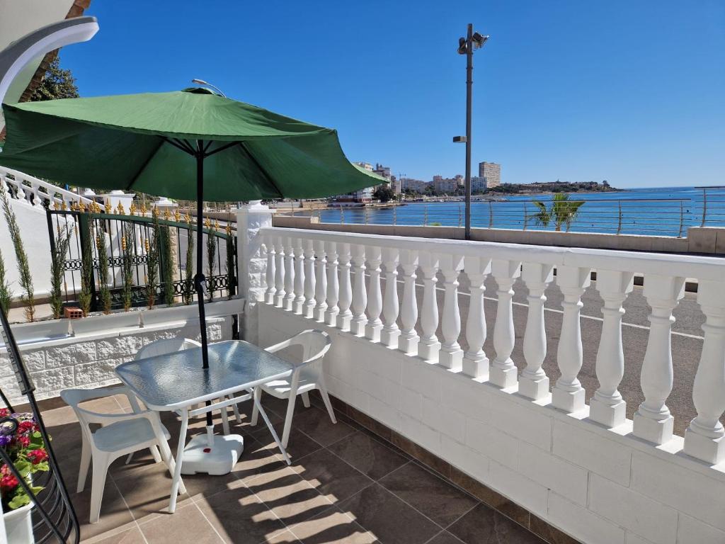 a table and chairs with an umbrella on a balcony at House totally refurbished in 2024, terrace in front of the sea, 1 min walk to the beach, aircon, wifi in Alicante