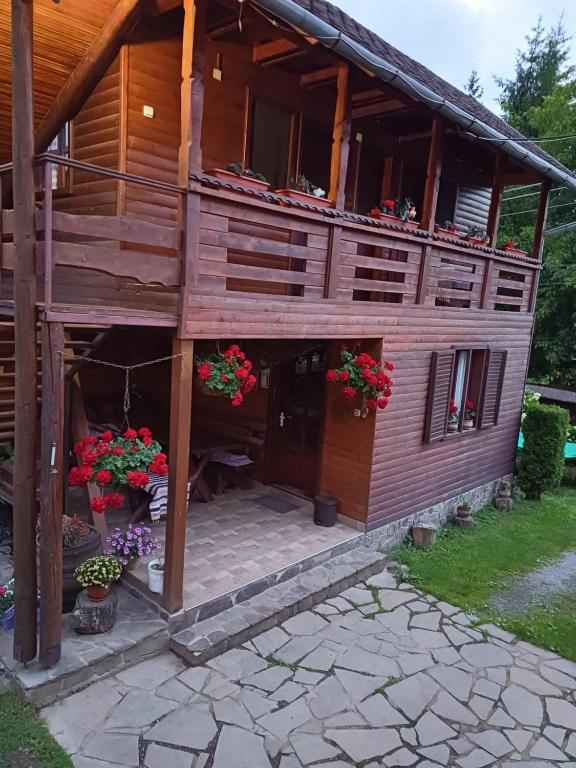 a large wooden house with flowers in front of it at Casa ,,Kiss-lak,, in Praid