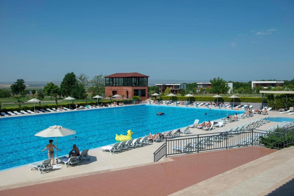 a large swimming pool with people sitting around it at Villa Ambassadori Kachreti Golf Resort in Gurjaani