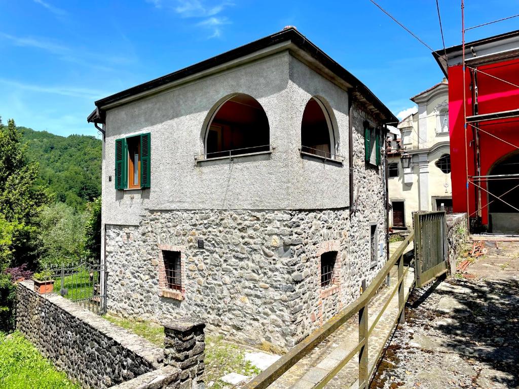 a stone building with two windows and a fence at Tre Terre in Mulazzo