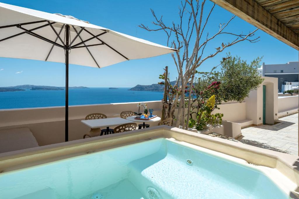 a swimming pool with an umbrella and the ocean at Passion Blue Villas in Oia