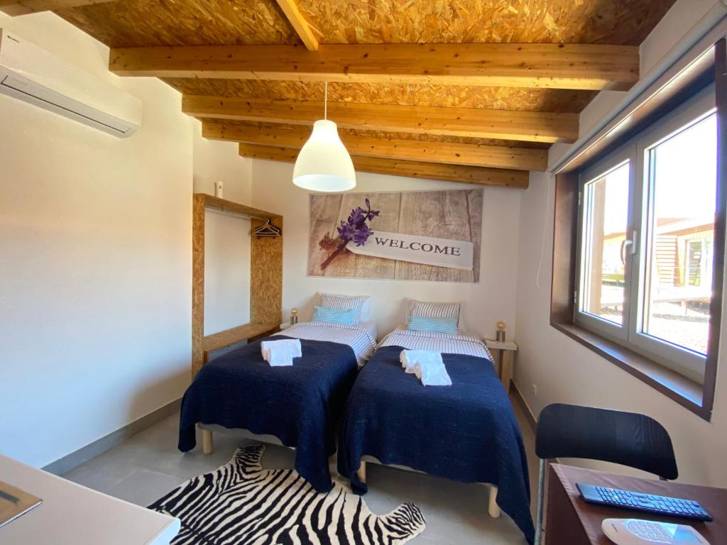 a bedroom with two beds with blue sheets and a window at Golden Halcyon - Ericeira Villas in Ericeira