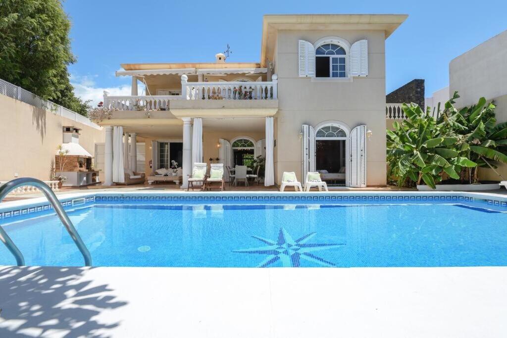 a villa with a swimming pool in front of a house at Bayside Concha House - Beachfront Oasis with Heated Pool in Playa Honda