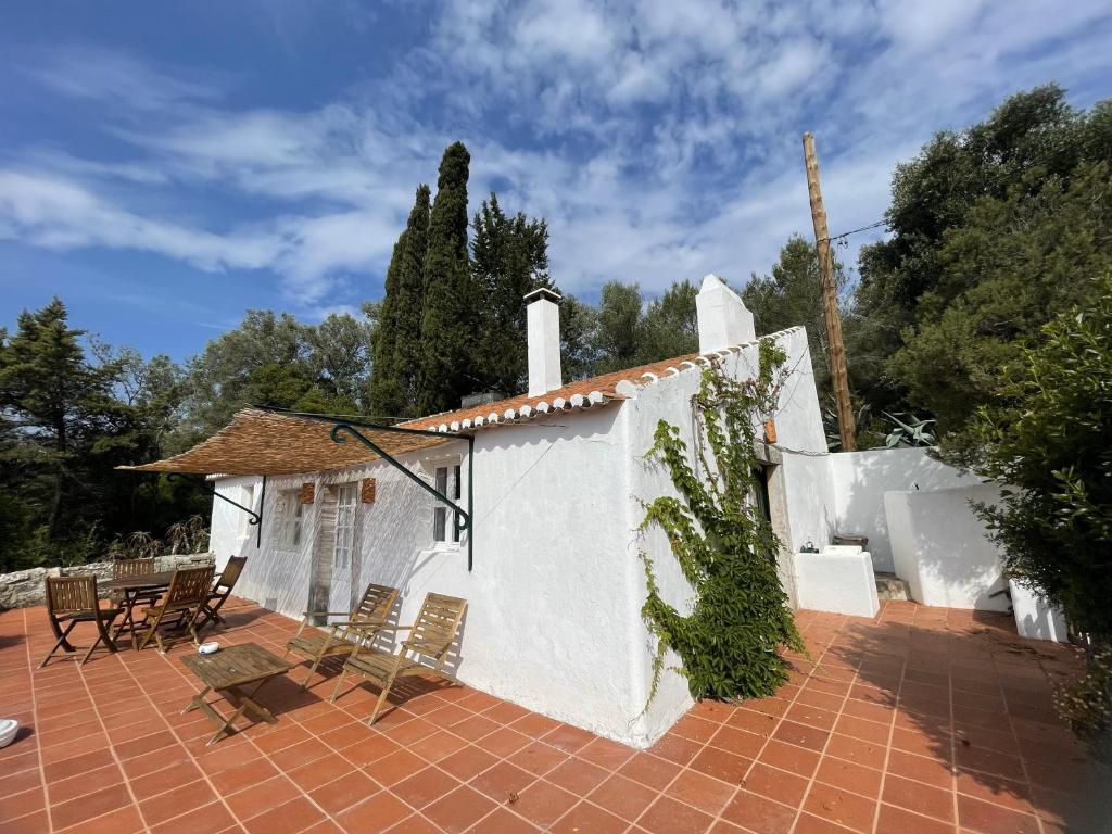 a white house with chairs and a brick patio at Casalinho do Farol, Serra da Arrábida in Setúbal