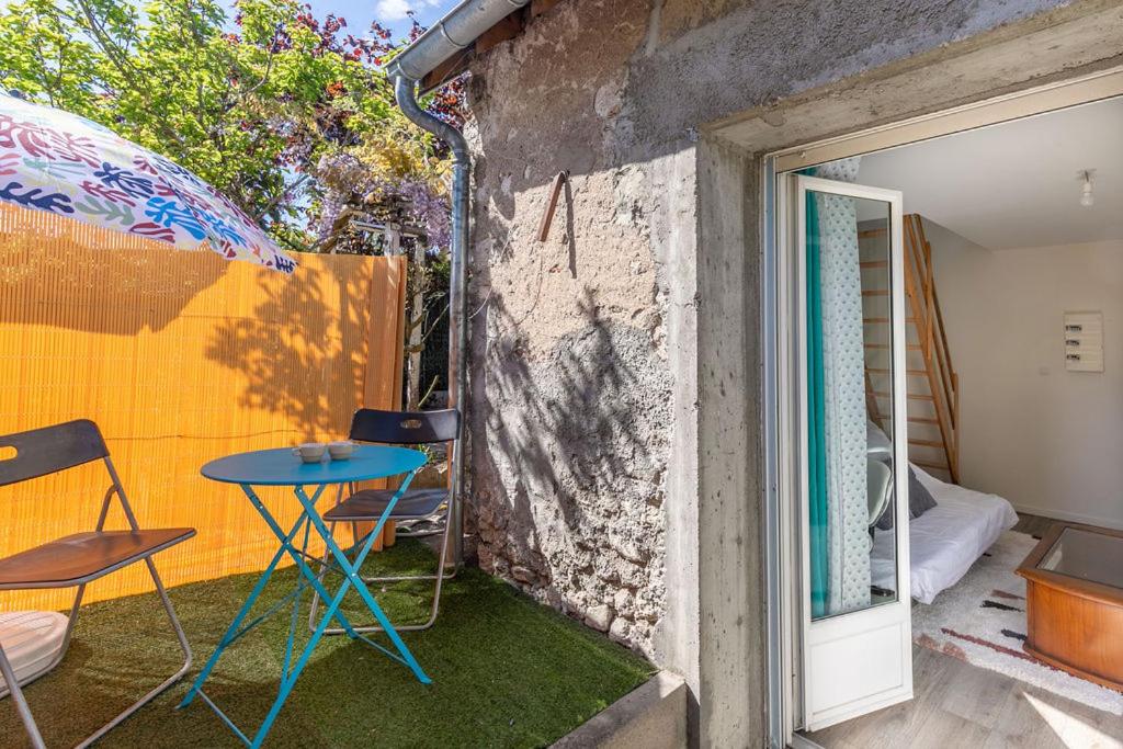 a patio with a table and chairs and an umbrella at Maisonnette cosy proche des 2 Gares et du centre ville Orléans in Orléans