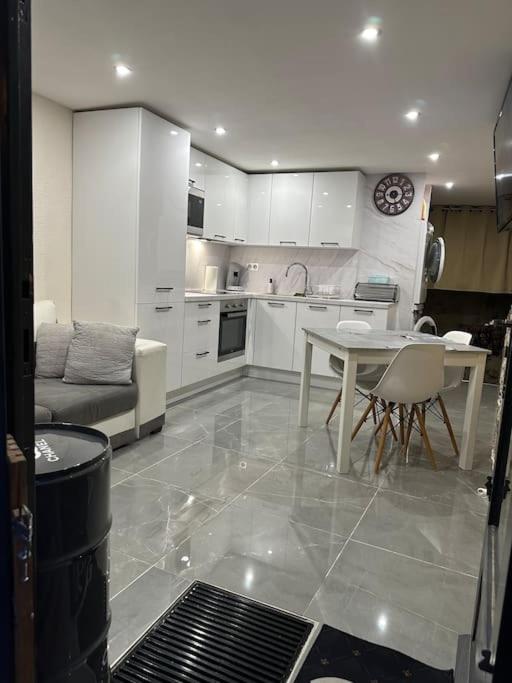 une cuisine avec des armoires blanches et une table et des chaises dans l'établissement Appartement tout équipé au cœur du village, à Fayence