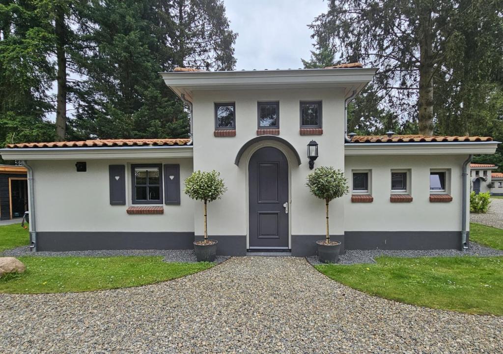 a white house with a door and two trees at Casa do Cervo, Boshof 6 Luxe met overdekt terras in Ermelo
