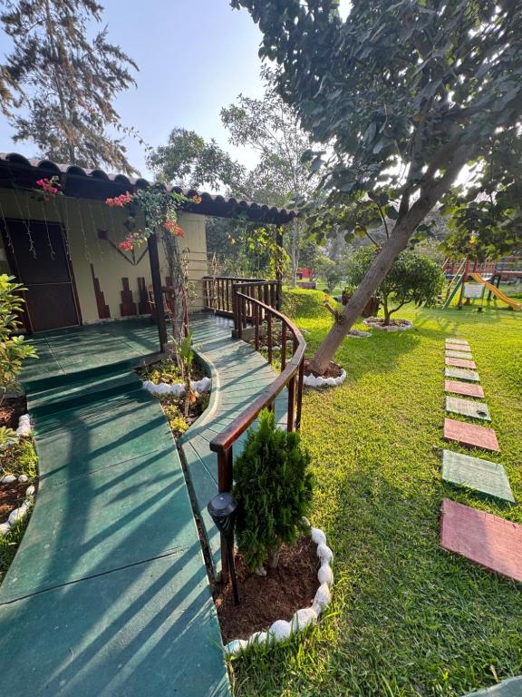 einen hölzernen Gehweg in einem Hof mit einem Haus in der Unterkunft Bungalow de 01 piso en casa de campo El Valle Inn in Cieneguilla