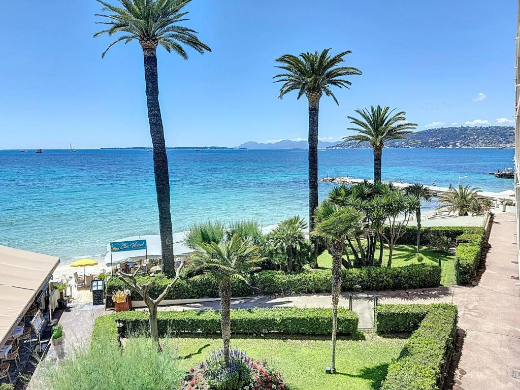 a view of a beach with palm trees and the ocean at La plus belle vue sur mer à Juan les Pins in Antibes