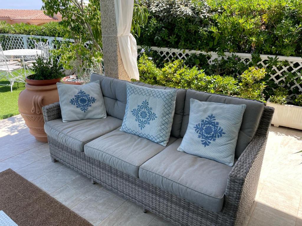 - un canapé en osier avec des oreillers sur la terrasse dans l'établissement Villa Adel, à San Teodoro