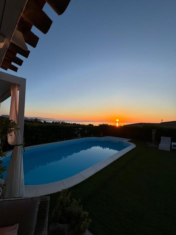 une piscine avec un coucher de soleil en arrière-plan dans l'établissement Villa Adel, à San Teodoro